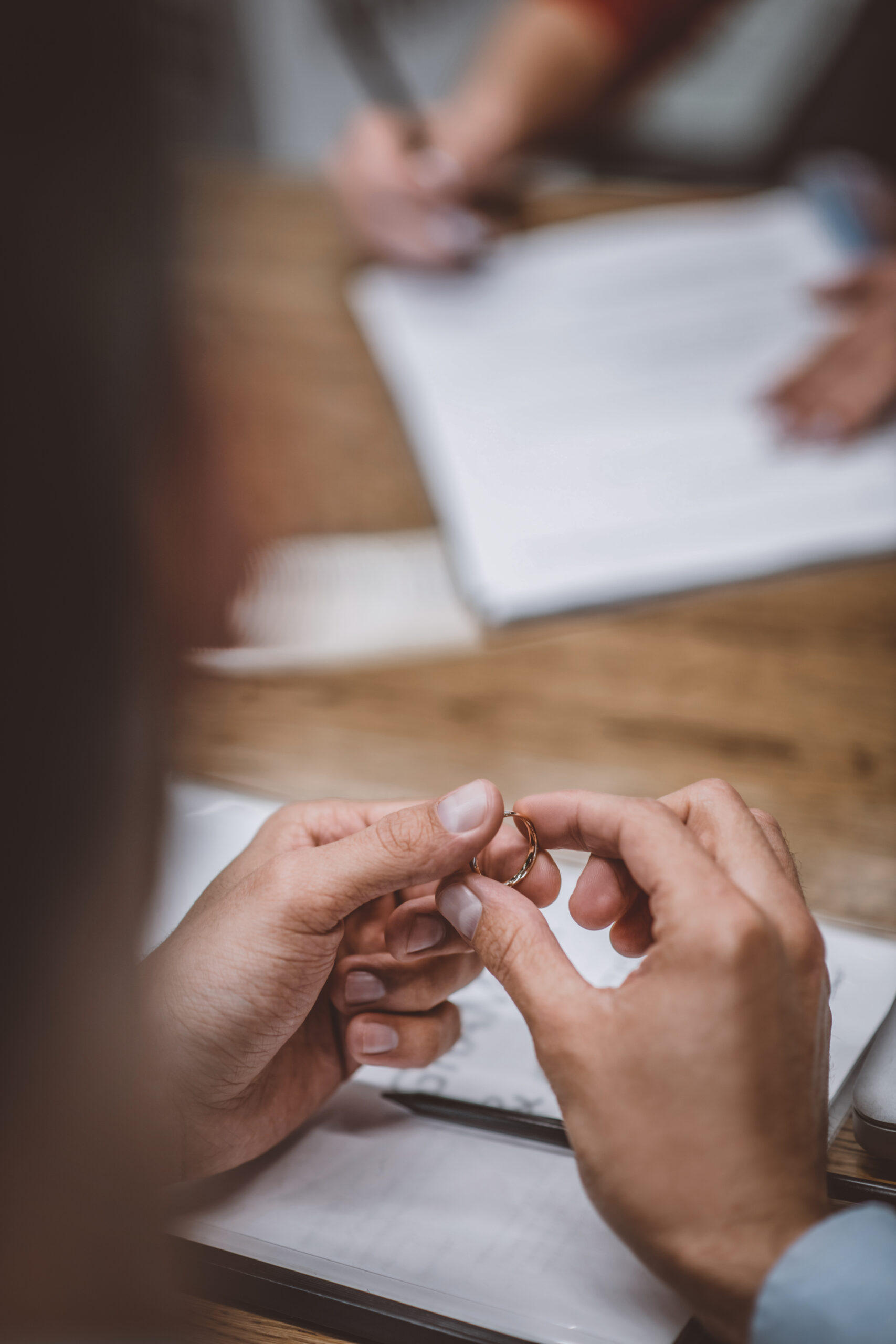 signing papers of divorce spouse holding ring in their hand